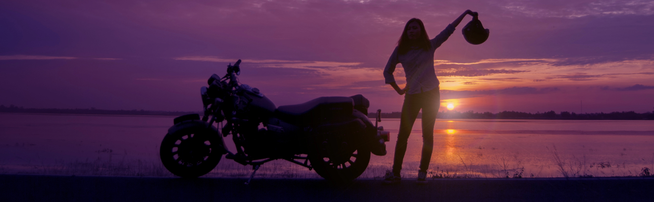 woman motorcyclist holding her helmet during sunset